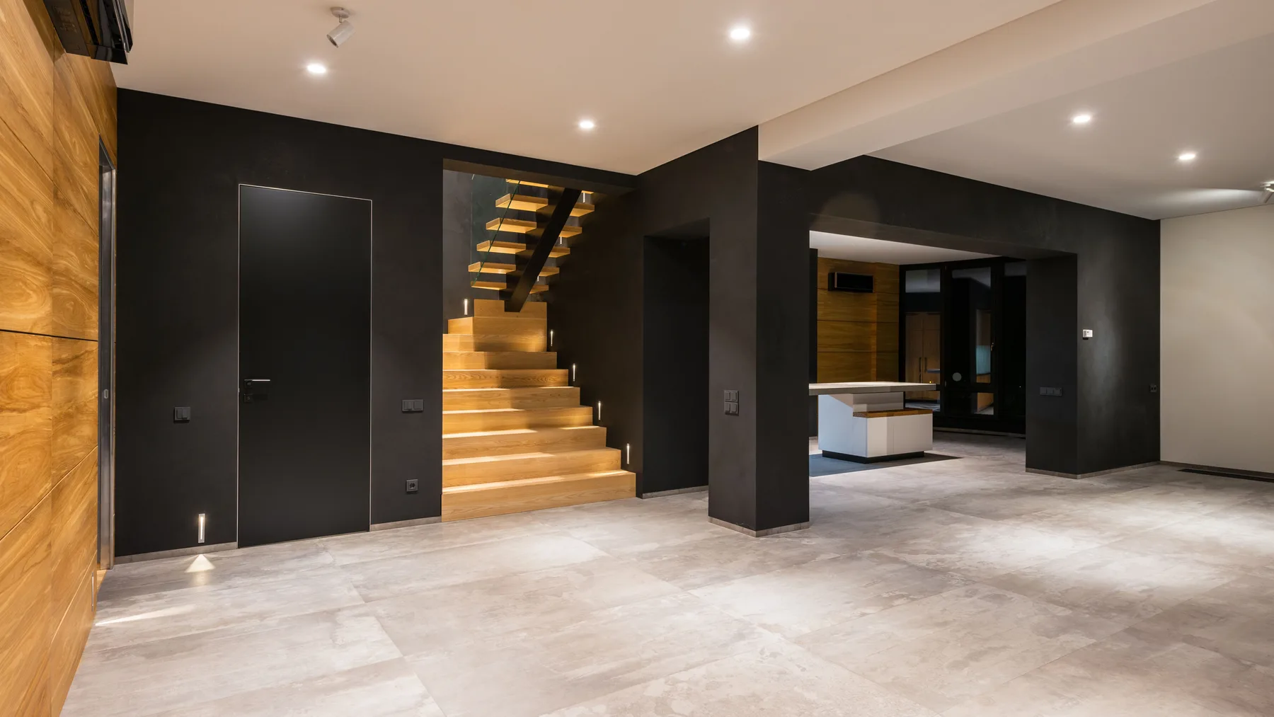 Cleared ground floor of a two-storey villa with an open wooden staircase, bare tiled floor and empty doorways