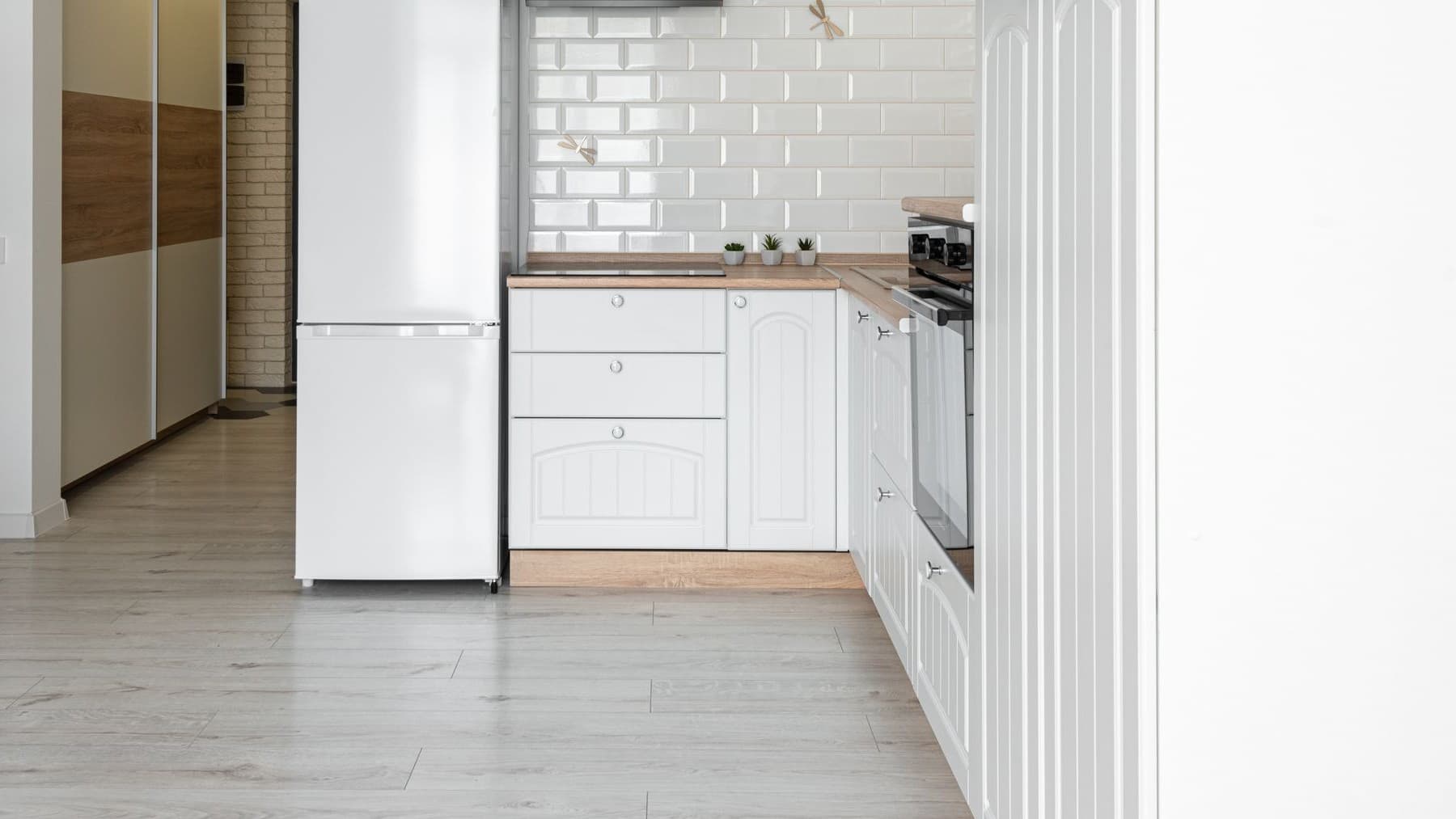 White freestanding fridge freezer standing beside white kitchen units in a bright apartment kitchen