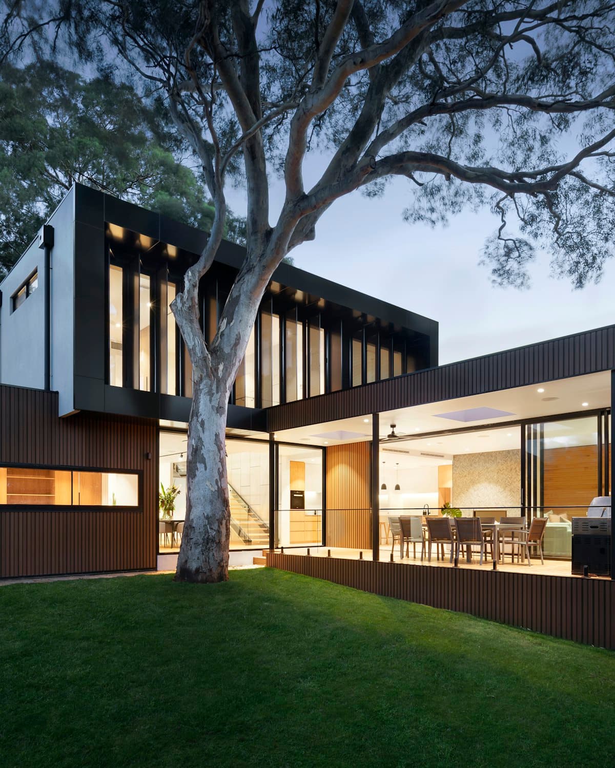 Modern Dubai villa lit at dusk, with an open courtyard and mature tree