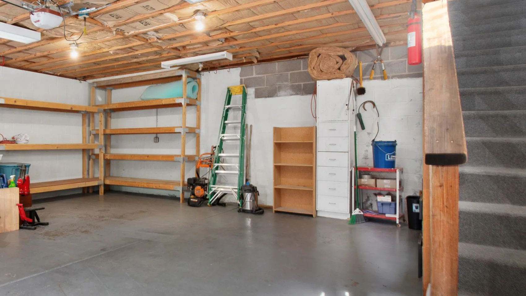 Villa garage with timber storage shelving, a stepladder, a filing cabinet and stored household items along the walls